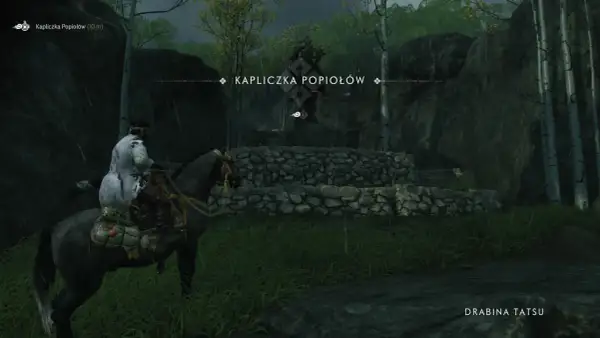 Samuraj na koniu zbliża się do Kapliczki Popiołów, ukrytej wśród drzew i skał.